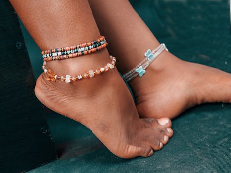 pexels-photo-20192867-20192867 Close-up of stylish beaded anklets adorning bare feet against a dark background.